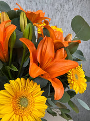 Arreglo Floral de Gerberas Amarillas y Lilies Naranja con Follaje Silver Dólar