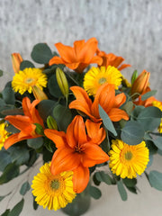 Arreglo Floral de Gerberas Amarillas y Lilies Naranja con Follaje Silver Dólar